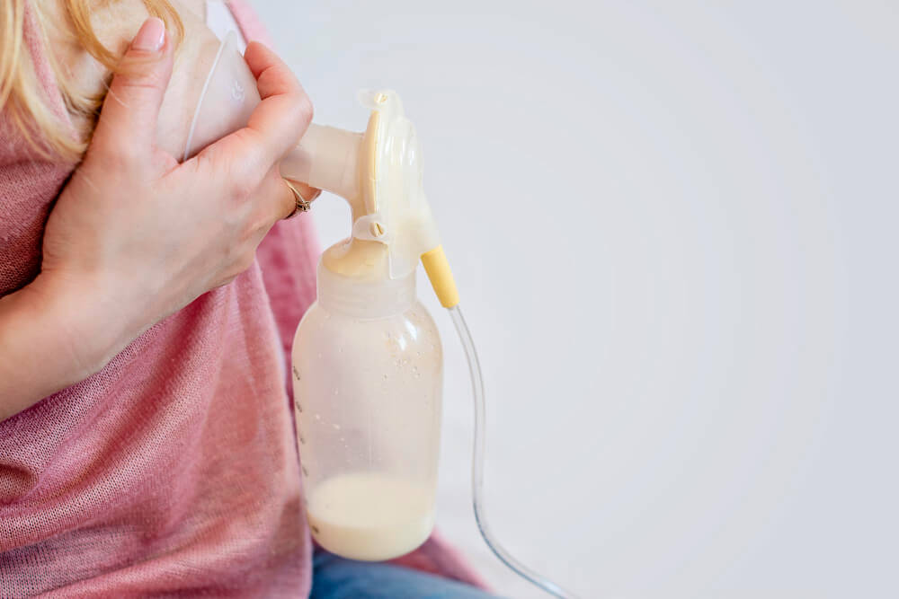 Biberon d'un tire-lait contenant seulement 20ml de lait maternel, avec une mère l'air anxieux.