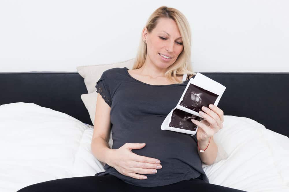 Femme enceinte regardant une échographie avec un air rassuré.