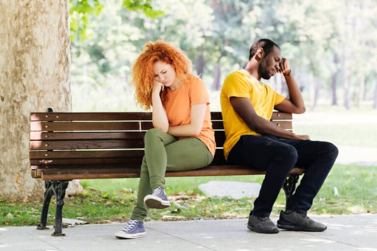 Couple assis dos à dos sur un banc, illustrant les différences de caractère et l'incompréhension malgré l'amour