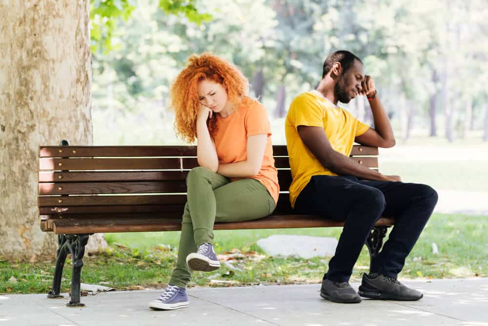 Couple assis dos à dos sur un banc, illustrant les différences de caractère et l'incompréhension malgré l'amour
