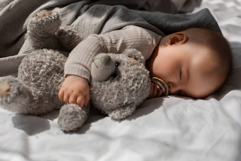 Bébé de 2 mois dormant dans son lit avec un doudou couvrant son nez et sa bouche