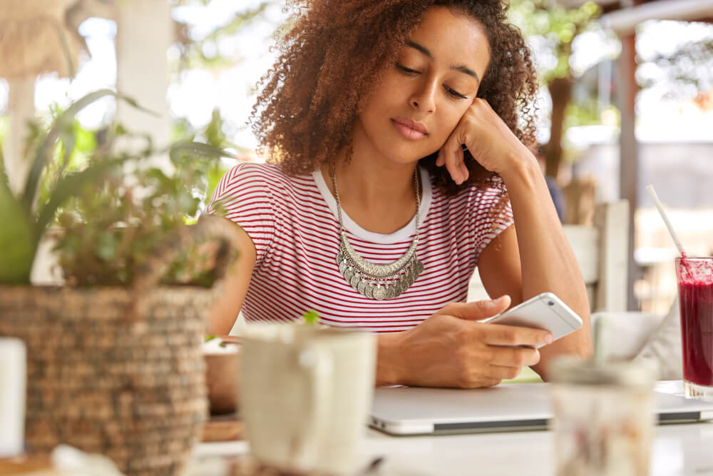 Personne hésitant à répondre à un SMS reçu sur son téléphone pendant une pause dans sa relation de couple