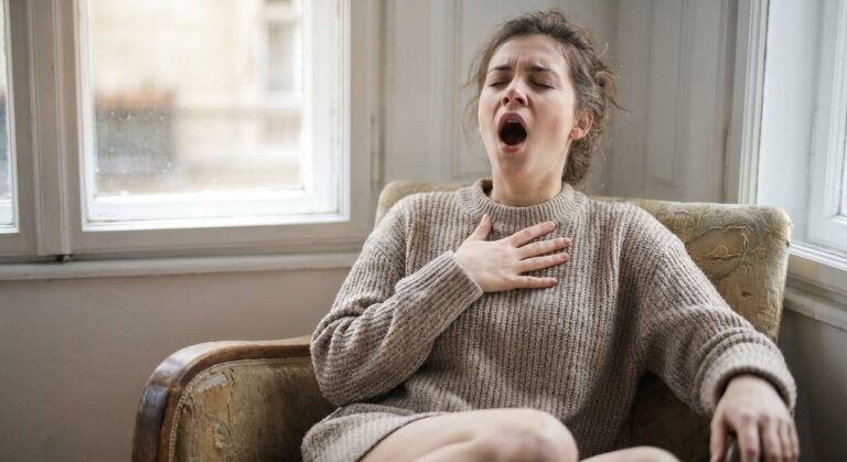 Jeune femme soupirant et bâillant profondément pour tenter de retrouver une respiration satisfaisante