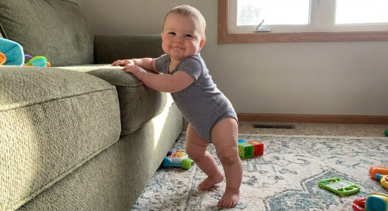 Bébé fier s'agrippant au bord du canapé pour se mettre debout tout seul