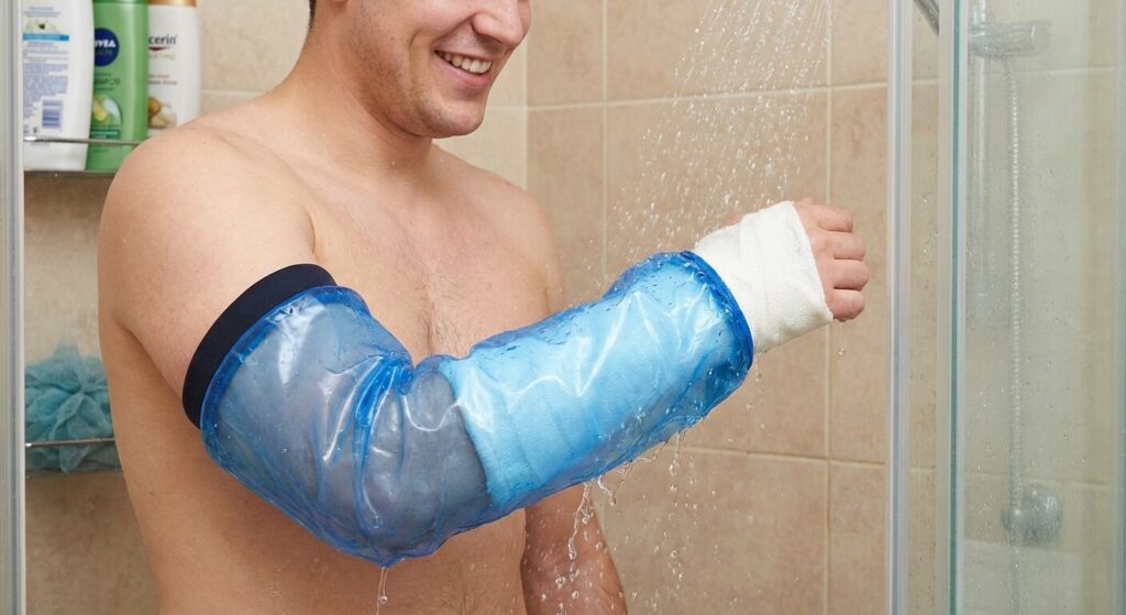 Plâtre mouillé : Que faire pour éviter les complications ? 3 Patient utilisant un manchon en plastique médical étanche pour protéger le plâtre de son bras pendant la douche