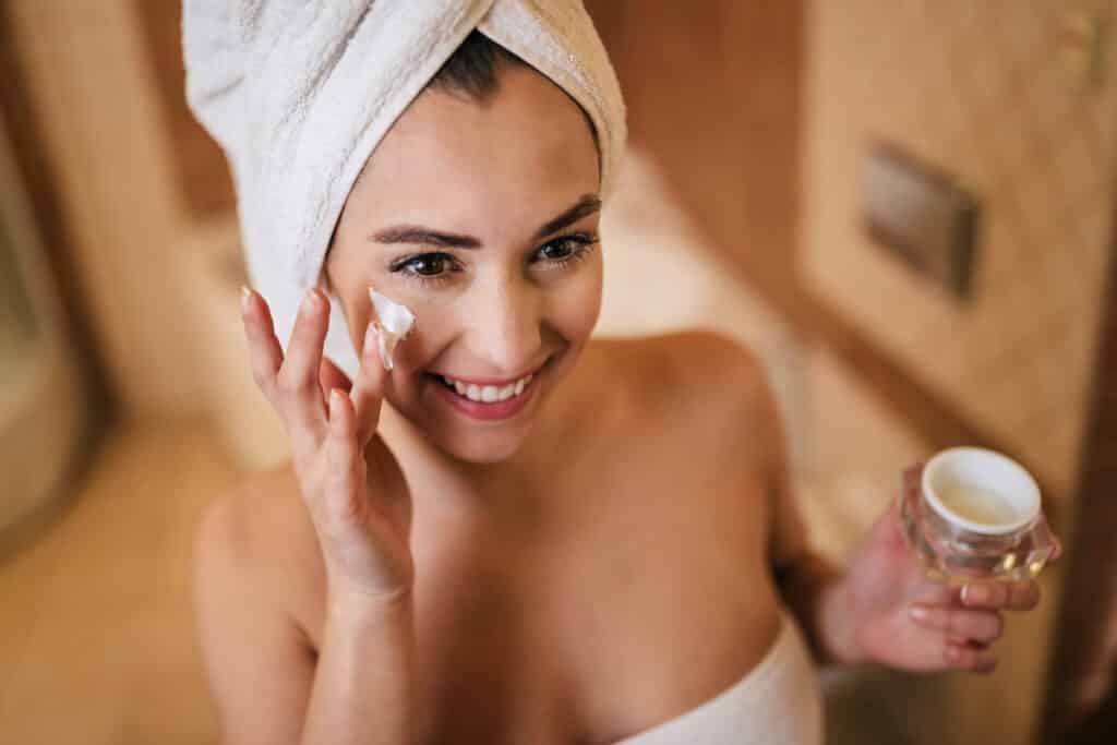 Une personne appliquant une crème hydratante sur son visage lors de sa routine du matin.