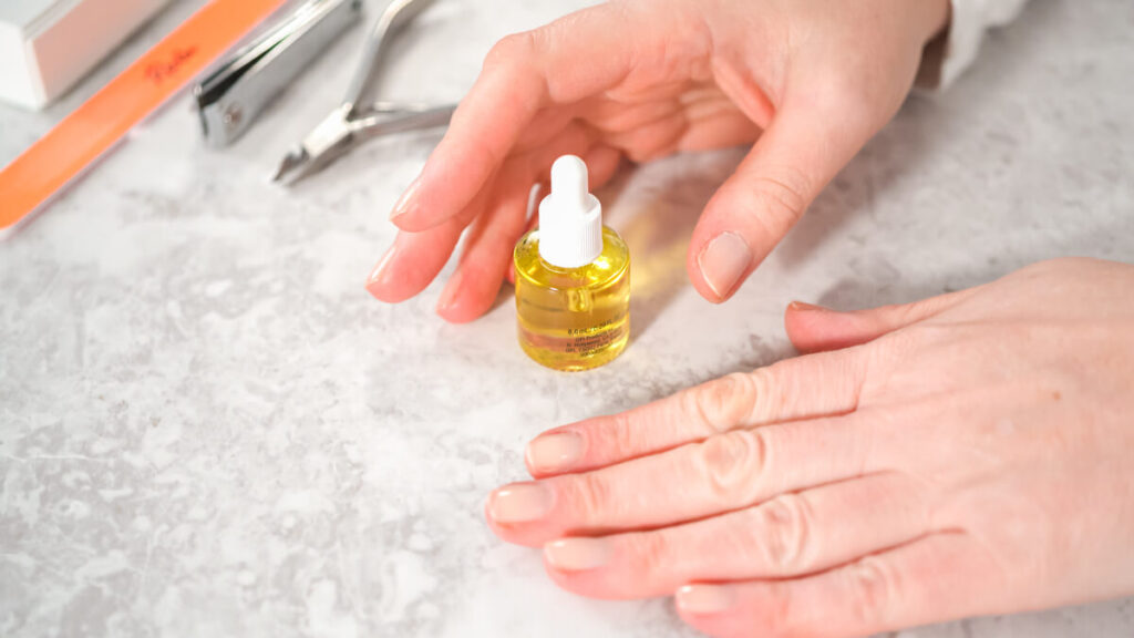 Ongle qui ne pousse pas, causes et solutions biologiques 3 Application d'une huile de soin nourrissante au pinceau sur la racine d'un ongle.