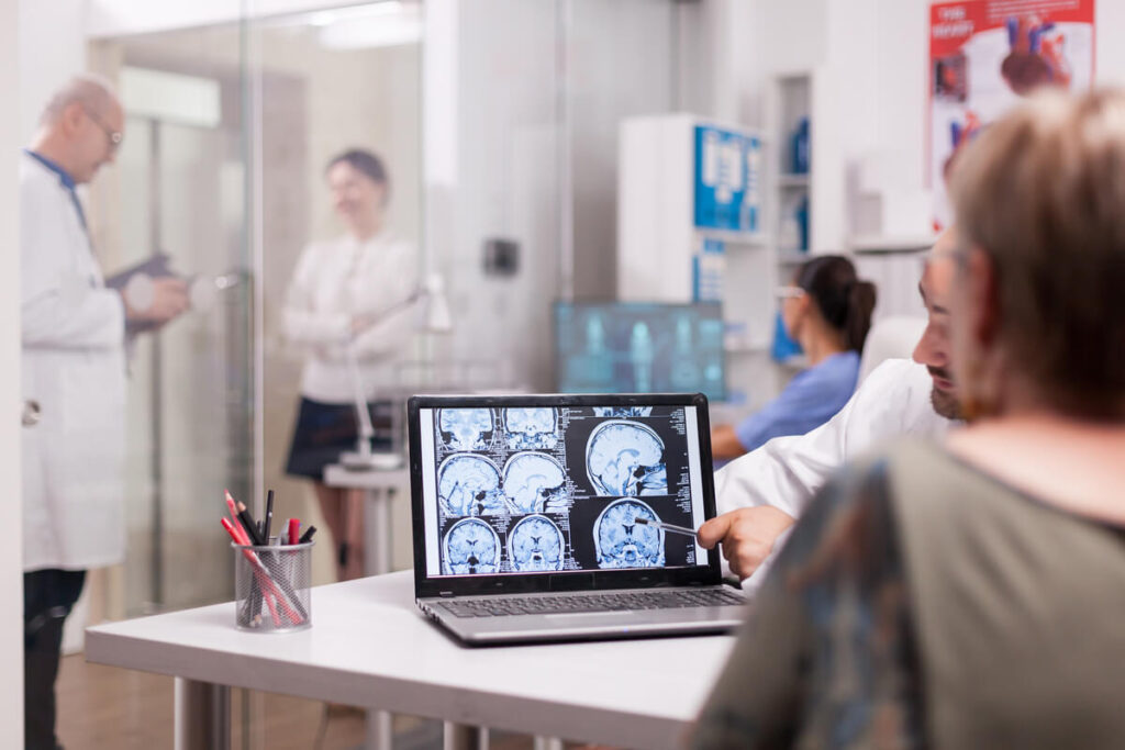 Un médecin neurochirurgien analysant une IRM cérébrale pour accorder une autorisation de voyage à son patient.