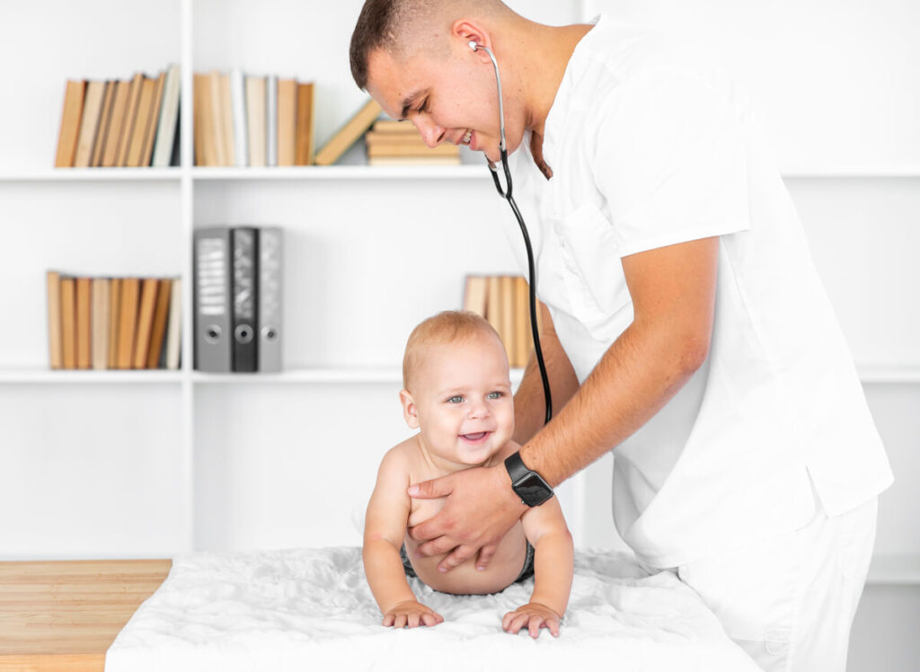 Je n'ai pas fait la visite des 9 mois de bébé : conséquences et solutions 2 Un médecin pédiatre examinant joyeusement la motricité d'un grand bébé de 9 mois lors d'un examen médical.