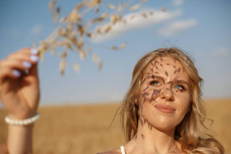Une femme souriante en extérieur, protégeant son épiderme des effets de la pollution et des rayons du soleil.