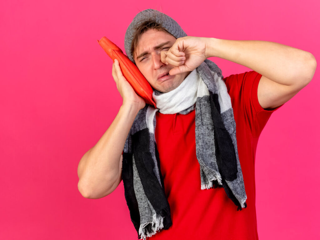 Une personne souffrant d'une rage de dents intense, appliquant une compresse froide sur sa joue gonflée.