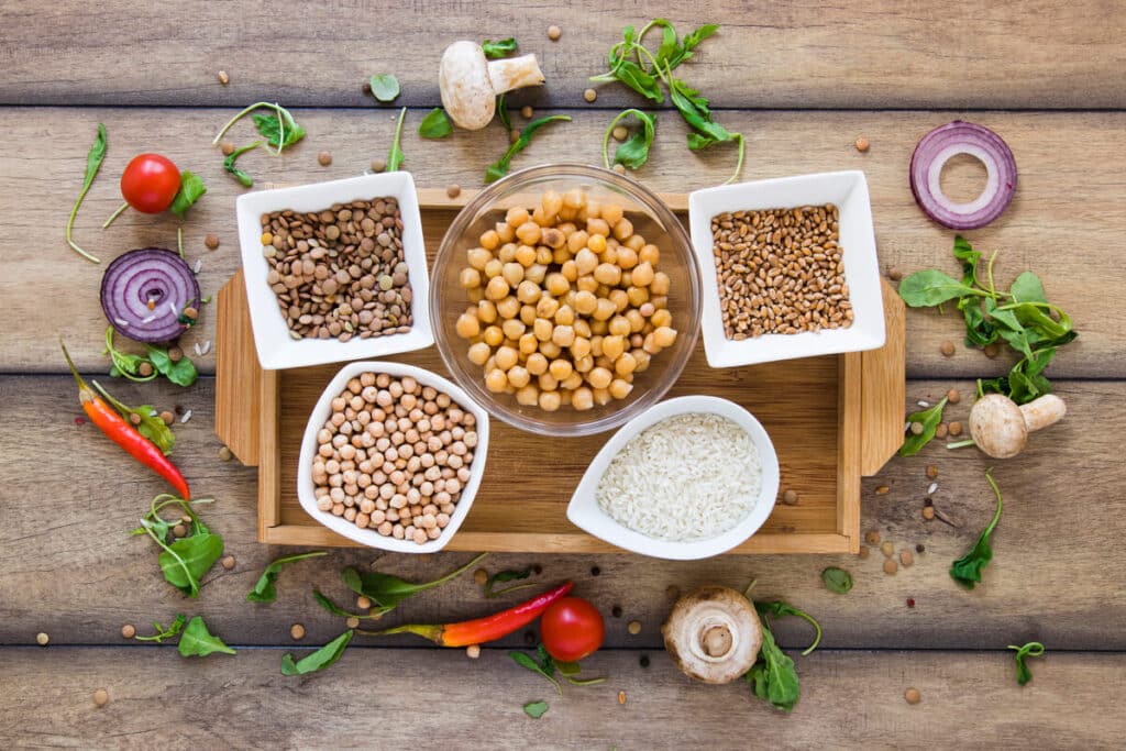 Un assortiment de protéines végétales dans des bols en verre comprenant des lentilles, du tofu, du quinoa et des graines.