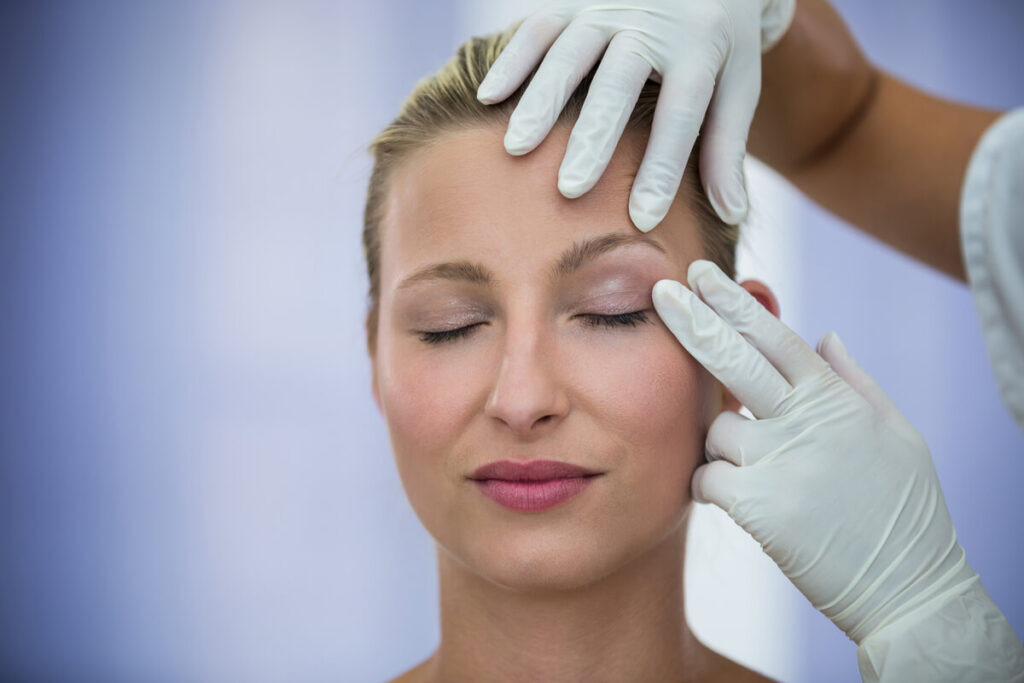 Un chirurgien esthétique traçant des repères précis sur la paupière supérieure d'une patiente avant une blépharoplastie.