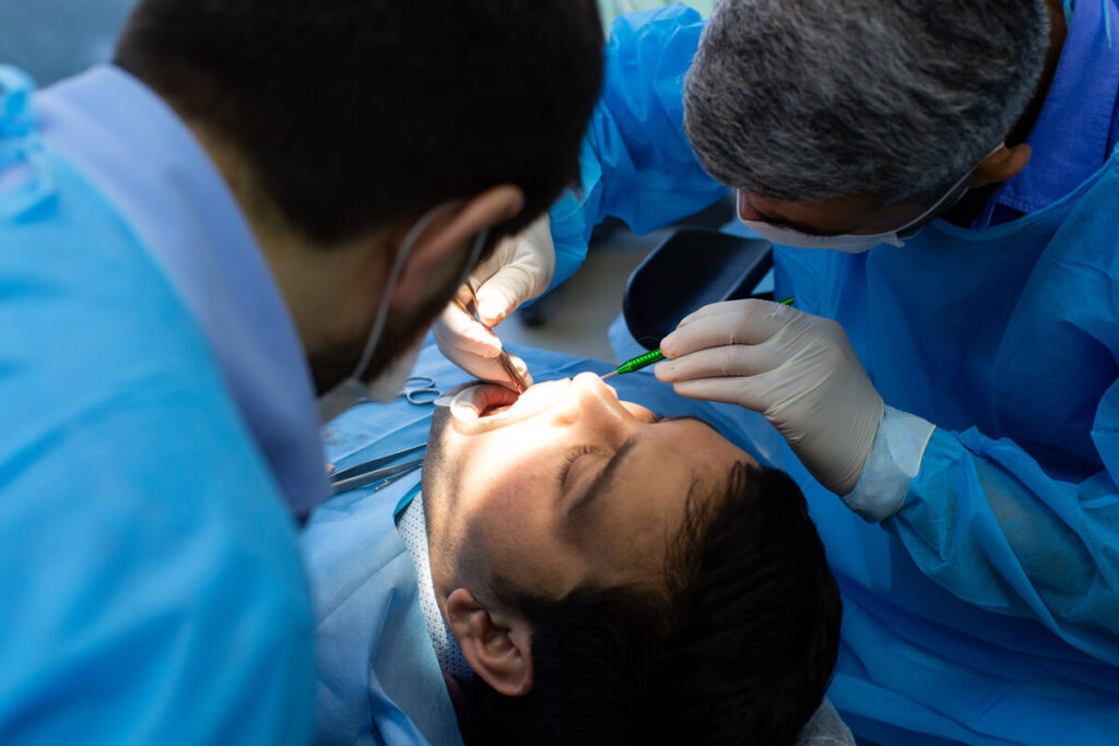 Un chirurgien-dentiste ajustant une prothèse dentaire moderne dans la bouche d'un patient.