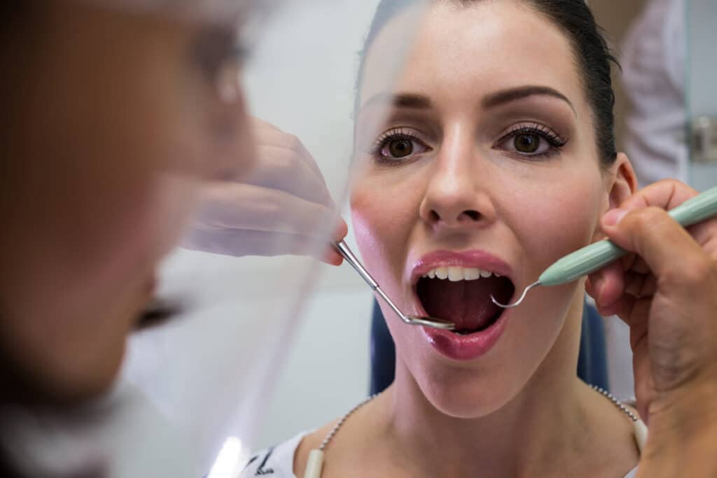 Polype pulpaire : définition, causes et traitement 2 Un dentiste examinant la bouche d'un patient à l'aide d'un miroir de contrôle.