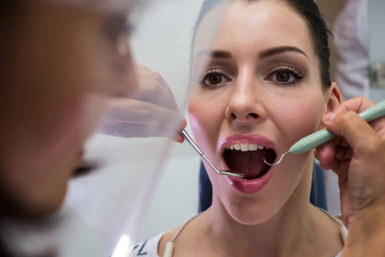 Accueil 3 Un dentiste examinant la bouche d'un patient à l'aide d'un miroir de contrôle.