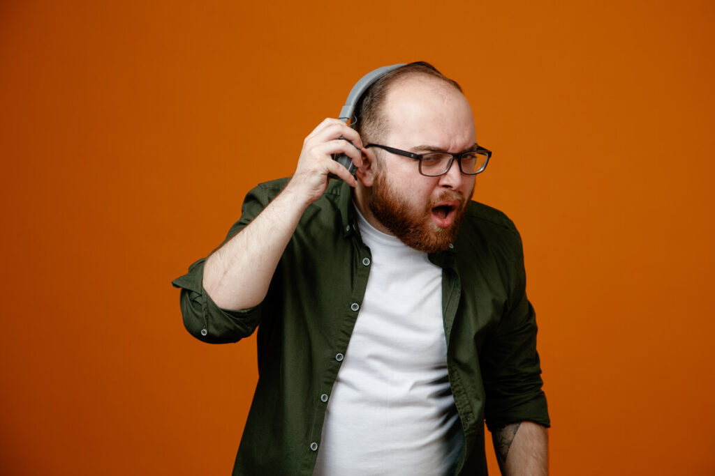 Une personne se tenant l'oreille avec une expression de gêne face à un sifflement auditif.