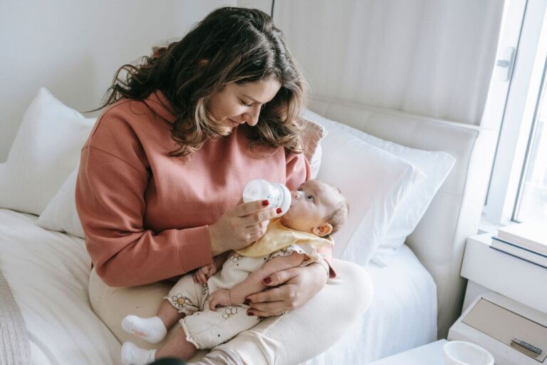 Un bébé qui boit son biberon de lait avec appétit dans les bras de son parent.