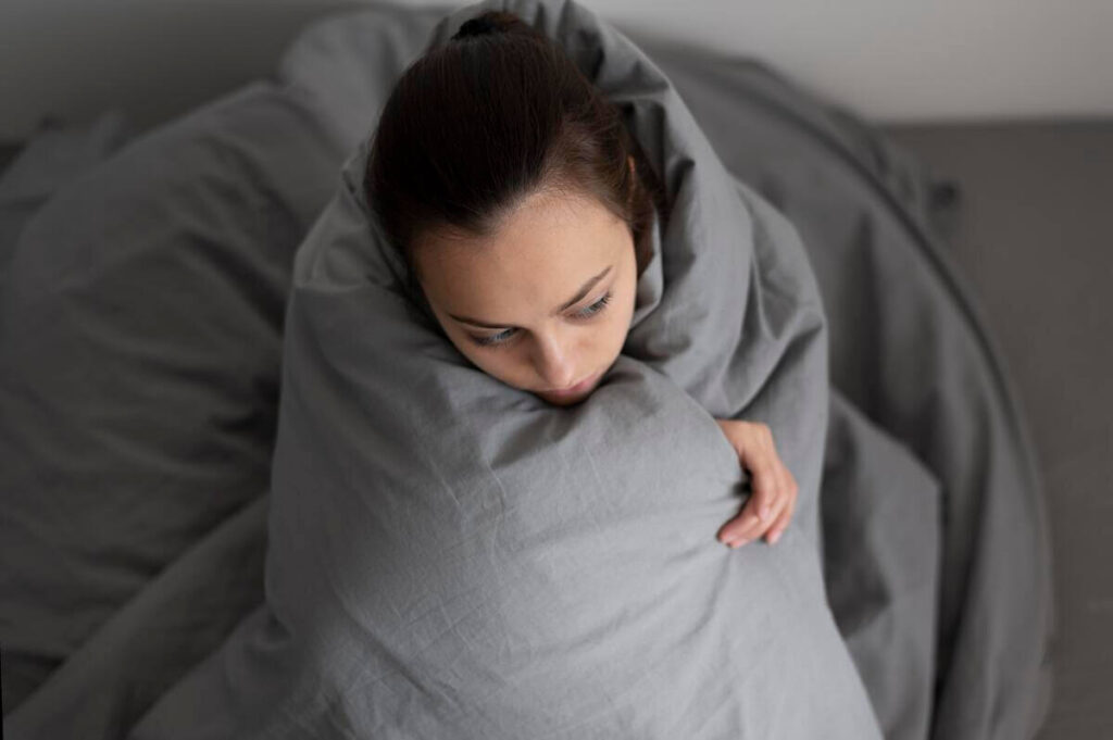 Une personne au sommeil agité se retournant au milieu de ses draps pendant la nuit.