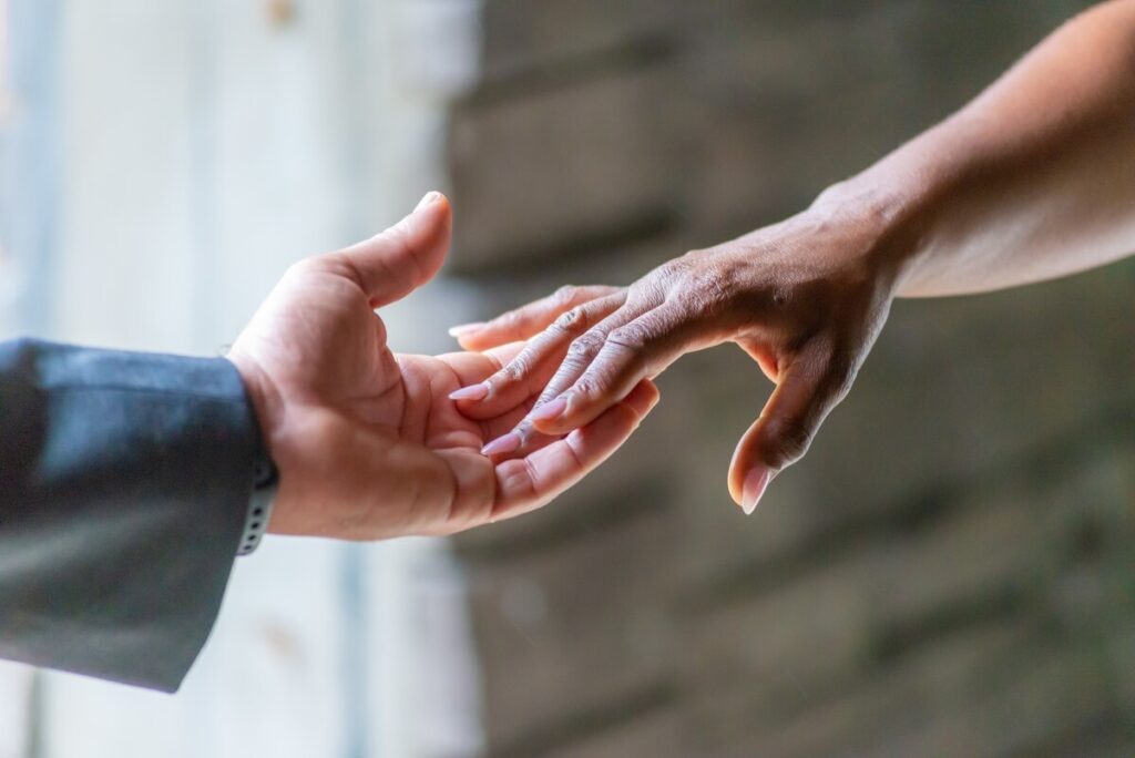 Pourquoi consulter un thérapeute de couple ? 3 Deux mains qui se serrent chaleureusement au cours d'une discussion, symbolisant la réconciliation et l'écoute mutuelle.