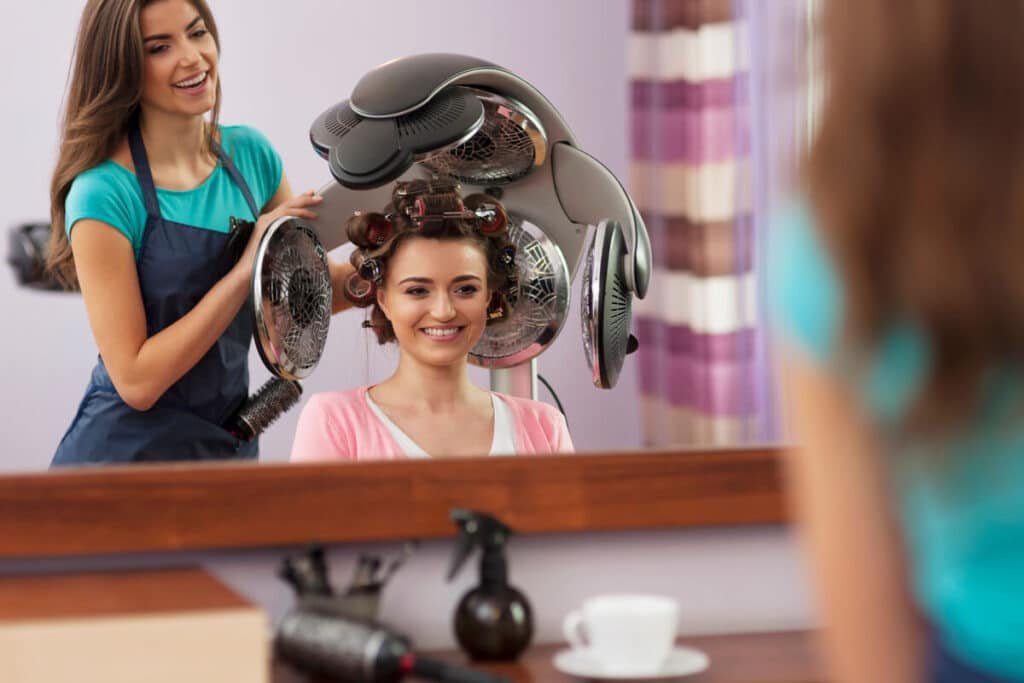 Adolescent réalisant une permanente bouclée avec des bigoudis dans un salon de coiffure.