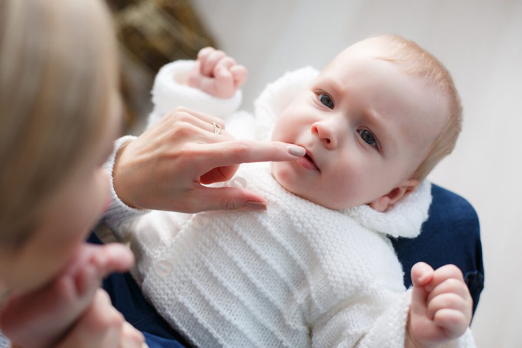 Parent effectuant un massage gingival doux à son bébé à l'aide d'un doigtier en silicone.