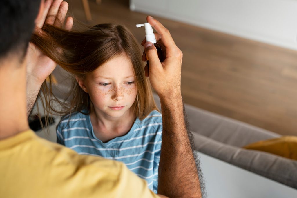 Application d'une lotion traitante anti-poux sur les racines des cheveux d'un enfant.