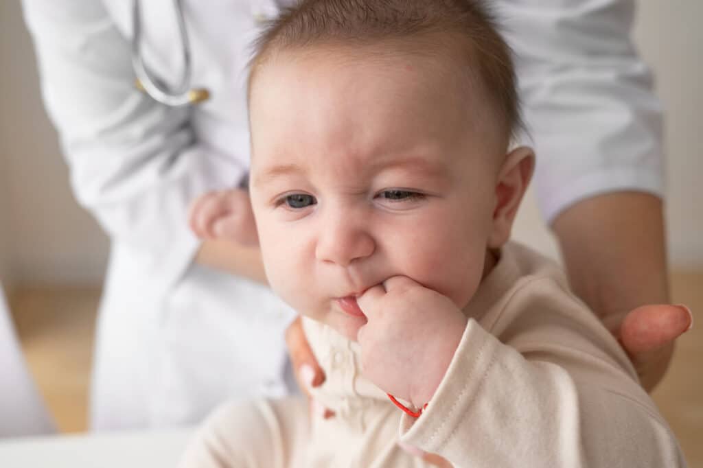 Poussée dentaire et fièvre à 39 °C chez le bébé : causes réelles et conduite à tenir 2 Bébé fiévreux portant un anneau de dentition pour soulager ses gencives gonflées.