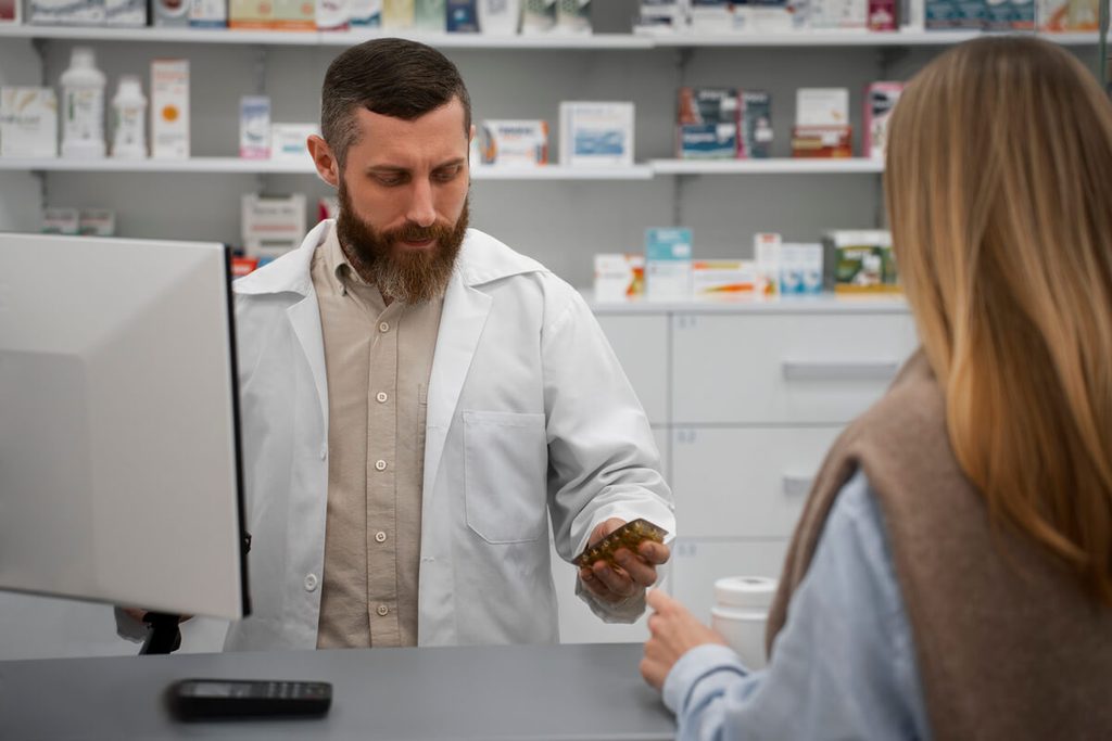 Pharmacien conseillant un patient au comptoir d'une officine sur les traitements sans ordonnance contre les vertiges.
