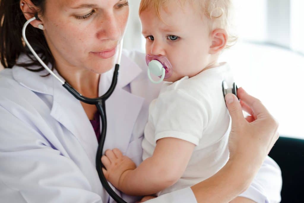 Poussée dentaire et fièvre à 39 °C chez le bébé : causes réelles et conduite à tenir 4 Pédiatre examinant les tympans d'un nourrisson pour rechercher une otite masquée par une poussée dentaire.