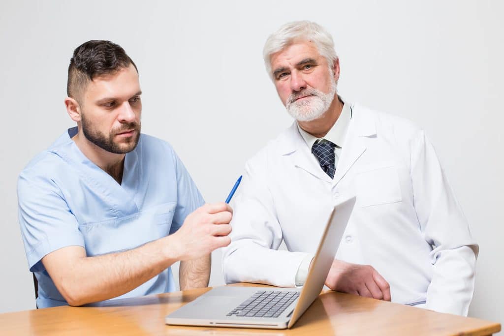 Médecin urologue expliquant l'anatomie génitale et les facteurs de développement testiculaire lors d'une consultation.