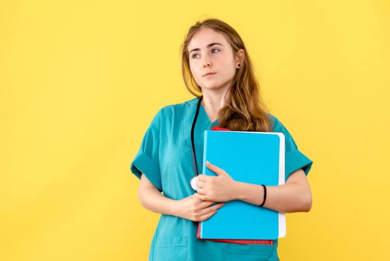 Étudiante infirmière en tenue de stage complétant son portfolio de compétences avec sa tutrice.