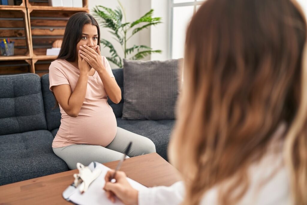 Femme enceinte tenant sa joue douloureuse en attendant une consultation dentaire d'urgence.