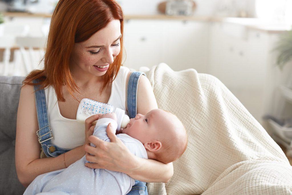 Je tire mon lait : quelle quantité donner à bébé par biberon 3 Maman donnant le biberon de lait maternel à l'horizontale selon la méthode du rythme adapté.
