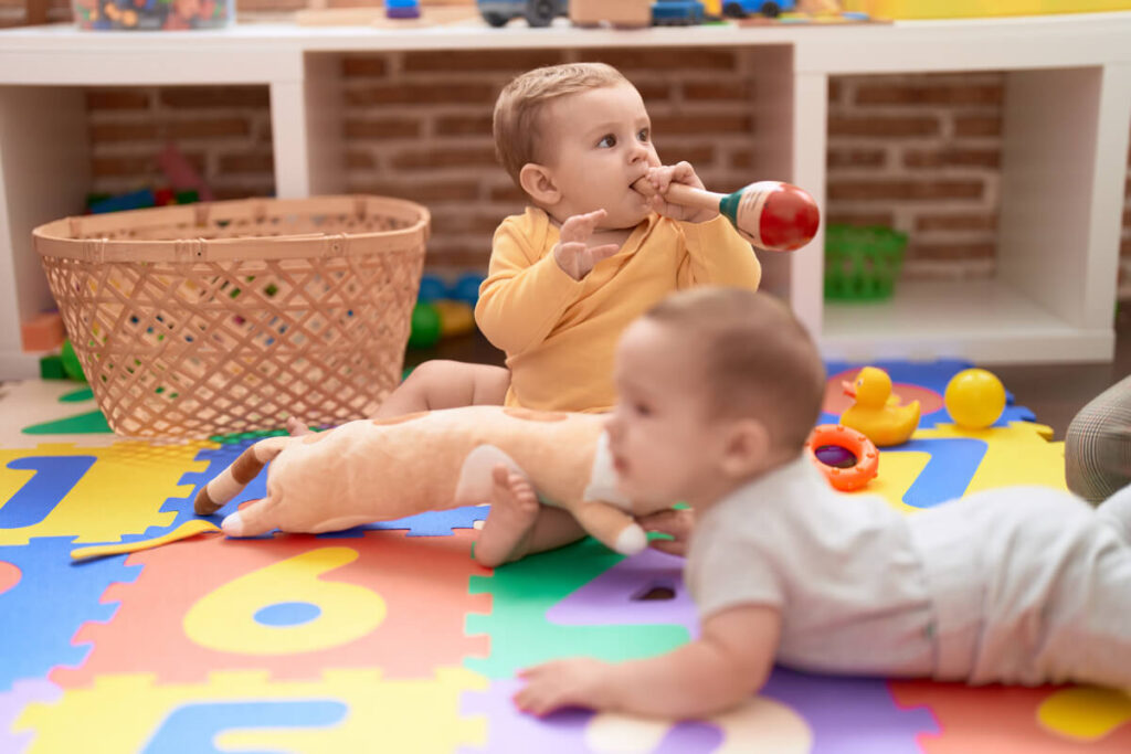 Bébé de 11 mois assis confortablement sur un tapis d'éveil jouant avec des cubes colorés.