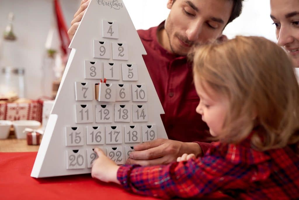 Comment désensibiliser son enfant au goût sucré sans frustration ? 3 Enfant ouvrant la case d'un calendrier de l'avent bonbon pour savourer une friandise quotidienne à heure fixe.