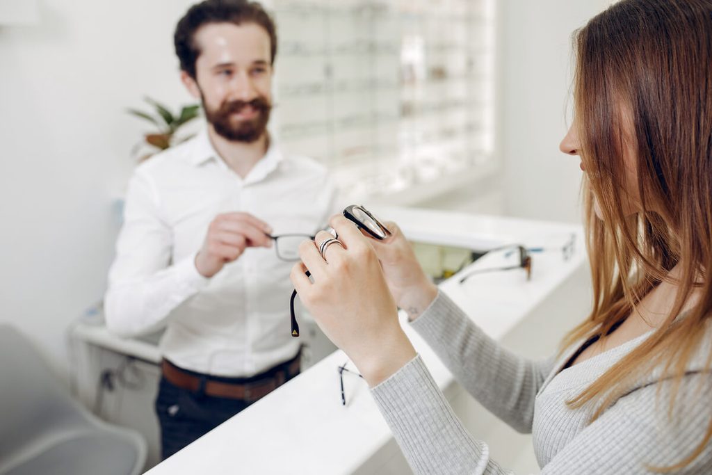 Optique, dentaire, audition : comment choisir sa mutuelle santé quand on a des soins coûteux ? 3 Opticien présentant une paire de lunettes équipées de verres correcteurs progressifs à un client.