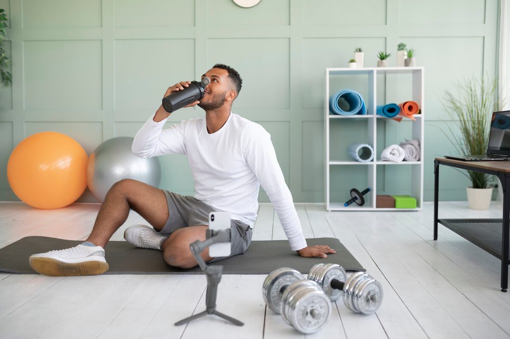 Combien de protéines par jour faut-il pour couvrir ses besoins ? 3 Sportif buvant un shaker de protéines après un entraînement physique pour la synthèse musculaire.
