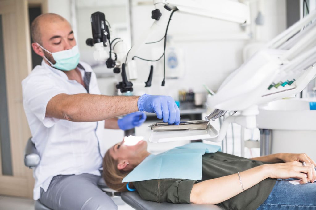 Dentiste nettoyant les canaux radiculaires d'une dent infectée au fauteuil de soins.
