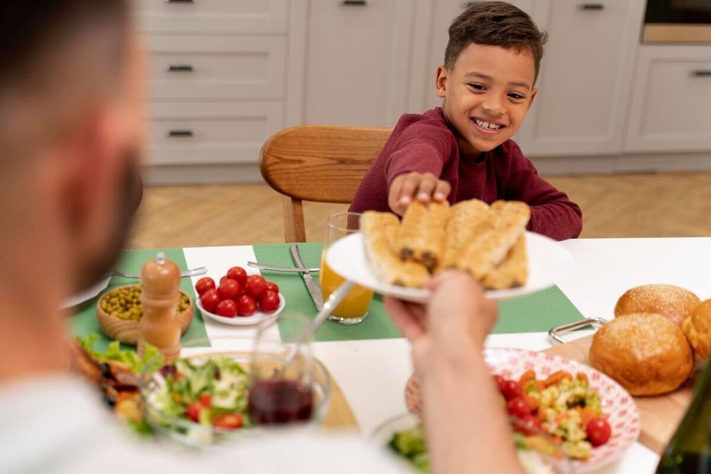 Comment désensibiliser son enfant au goût sucré sans frustration ? 4 Jeune enfant mangeant calmement son assiette de légumes à table en famille sans obligation de finir pour avoir un dessert.