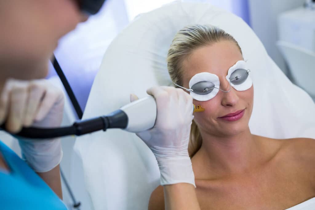 Dermatologue appliquant une pièce à main de laser vasculaire à colorant pulsé sur les rougeurs du visage.